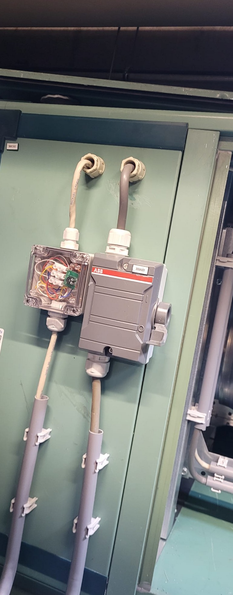 ABB schakelkast en doorzichtige aansluitdoos met kabelbuizen op een groene industriële unit